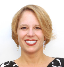 A woman in a black and white top smiles.