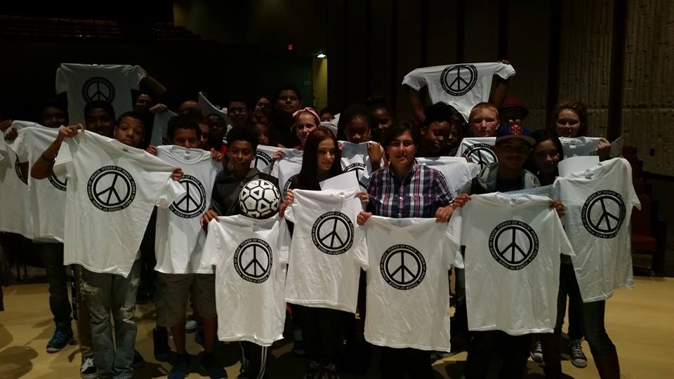 A group of people holding up t - shirts with peace signs on them.