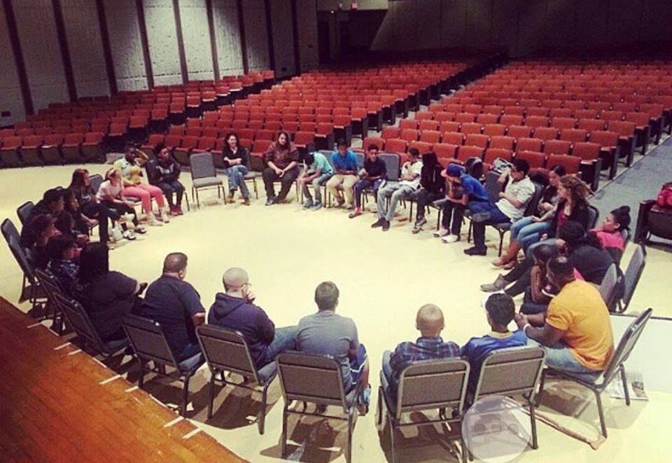 A group of people sitting in a circle in an auditorium.
