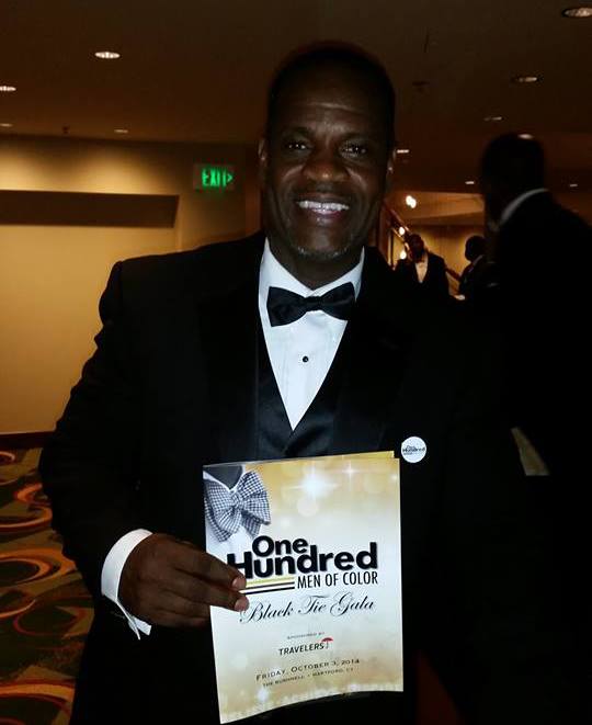 A man in a tuxedo holding an award.