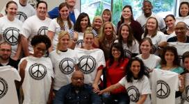 A group of people posing for a photo with peace sign t - shirts.