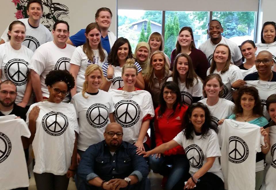 A group of people posing for a photo with peace sign t - shirts.