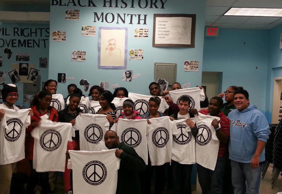 A group of people holding up black history month t - shirts.