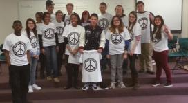 A group of people posing for a photo in front of a peace sign.