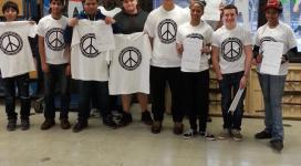 A group of people holding up t - shirts with peace signs on them.