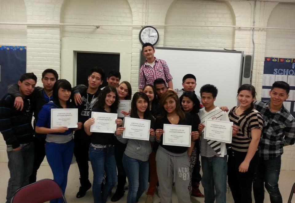 A group of people holding certificates in front of a classroom.