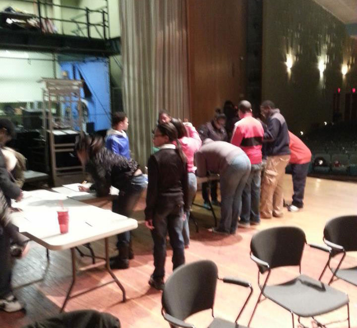 A group of people standing around a table in an auditorium.