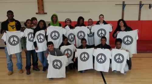 A group of people holding peace sign t - shirts in a gym.