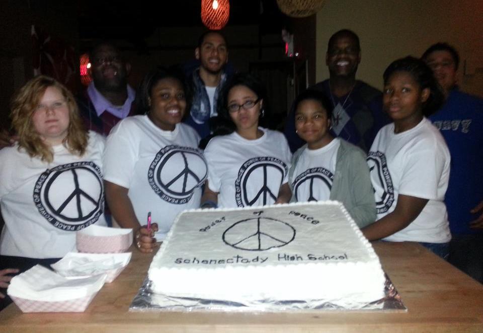A group of people posing in front of a cake.