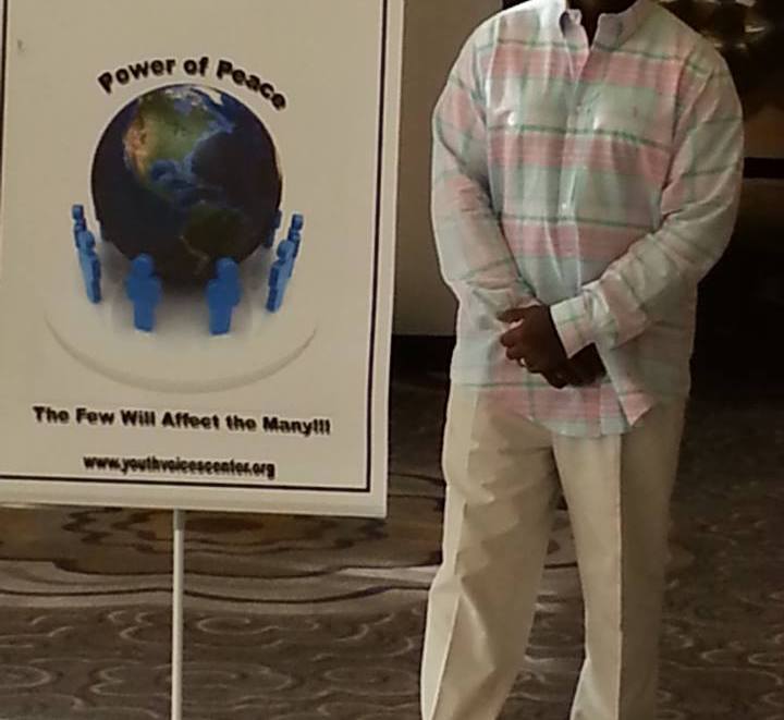 A man standing in front of a sign that says power of peace.