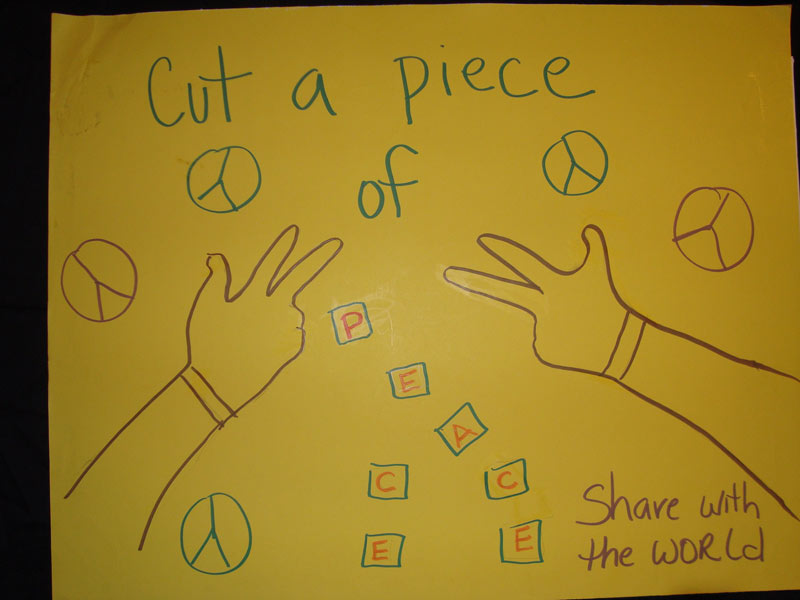 A yellow sign that says cut a piece of peace share with the world.