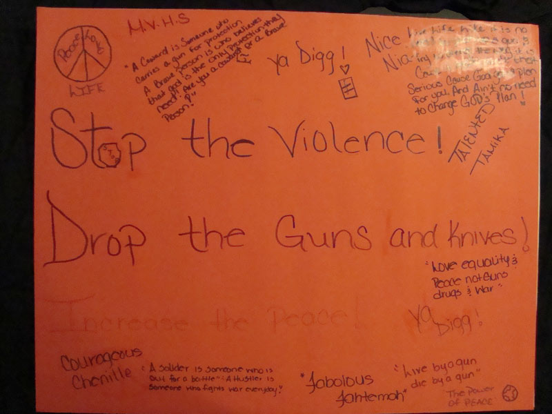 A poster that says stop the violence drop the guns and knives.