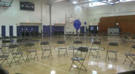 A gymnasium filled with chairs and balloons.