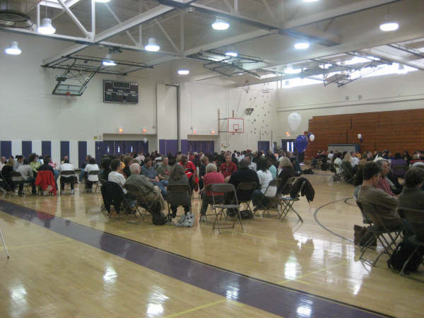 A group of people sitting in chairs in a gym.