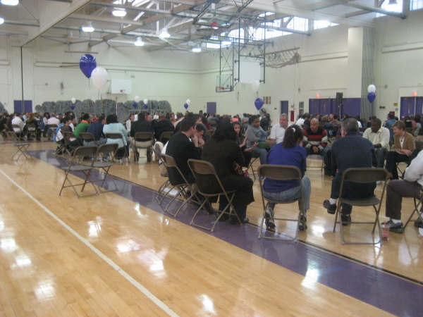 A group of people sitting in chairs in a gym.