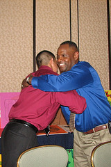 Two men hugging in front of a table.