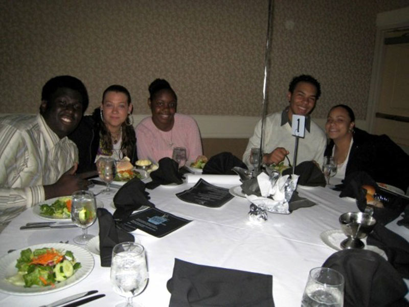 A group of people posing for a picture at a dinner table.