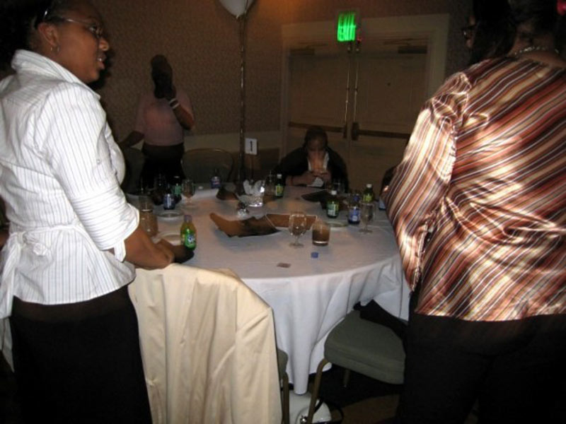 Two women standing around a table at a party.