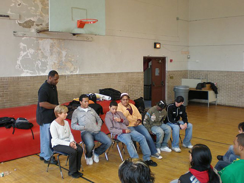 A group of people sitting on chairs in a gym.