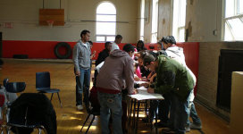 A group of people standing around a table in a gym.
