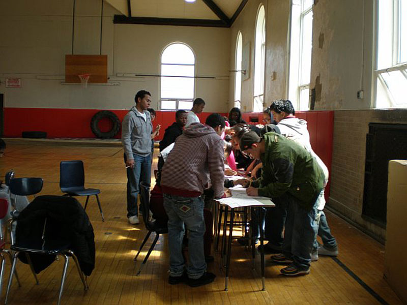 A group of people standing around a table in a gym.