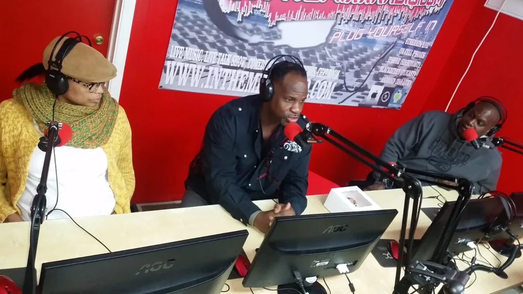 A group of people sitting at a table in a radio studio.