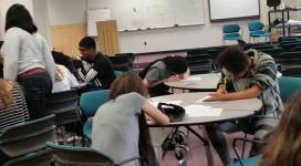 A group of people sitting at tables in a classroom.