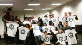 A group of people holding up t - shirts in a room.