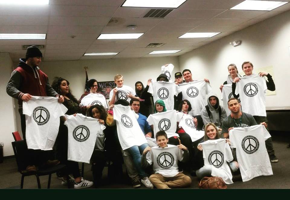 A group of people holding up t - shirts in a room.