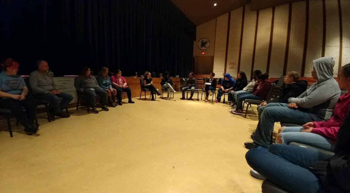 A group of people sitting in a circle in an auditorium.