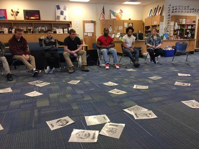 A group of people sitting on the floor in a classroom.